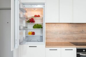 cocina con frigorífico blanco con la puerta abierta y verdura en el inteerior