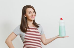 mujer sujetando jabón para limpiar frigorífico de acero inoxidable