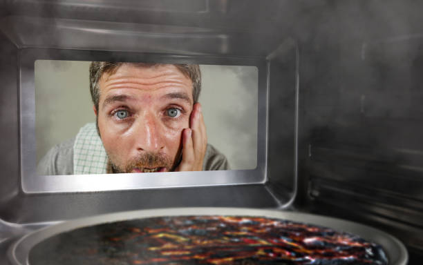 Hombre mirando un microondas quemado