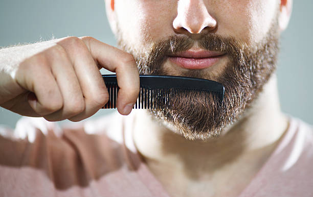 hombre de mediana edad peinando la barba tras pasar la afeitadora recortadora