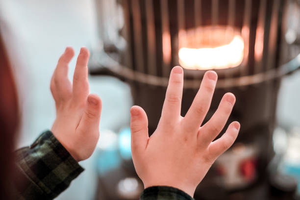 niño calentándose las manos en una estufa de gas
