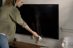Mujer limpiando pantalla de TV