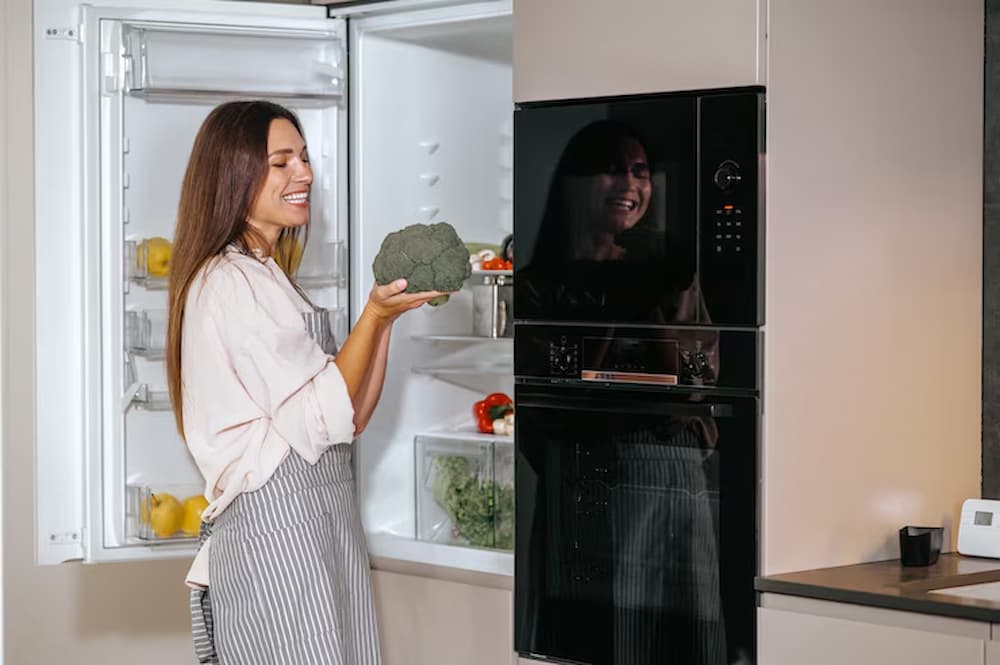 Mujer guardando brócoli en refrigerador