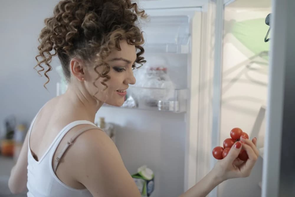 Mujer sacando uvas del frigorífico