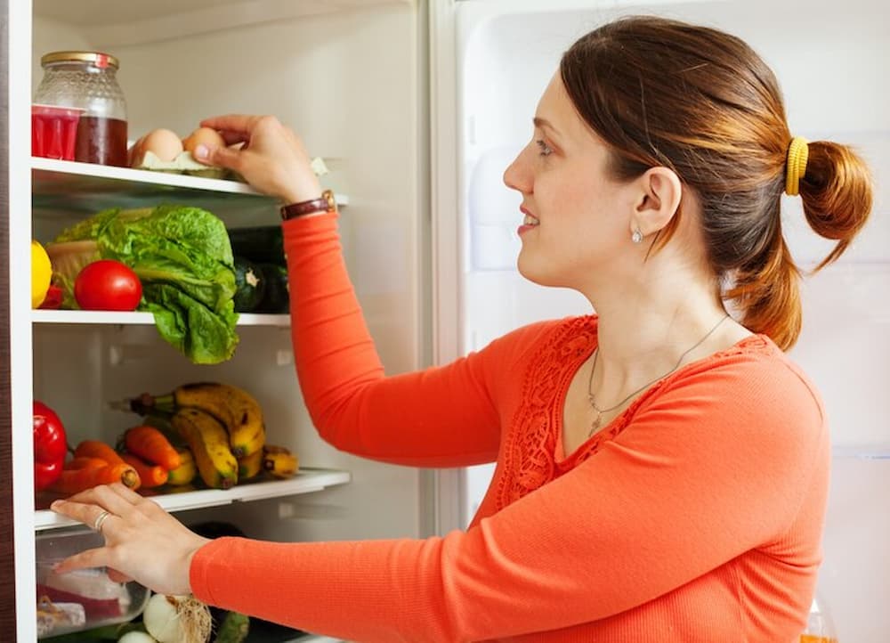 Mujer tomando huevos del frigorífico